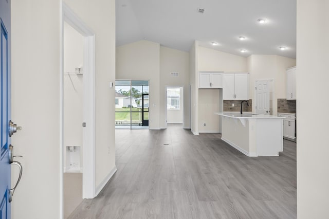 kitchen with white cabinetry, sink, a kitchen breakfast bar, light hardwood / wood-style flooring, and an island with sink