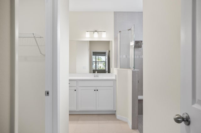 bathroom with a tile shower, tile patterned flooring, and vanity