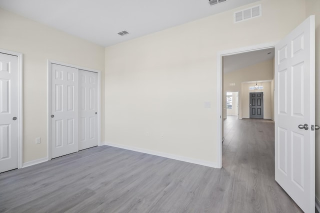 unfurnished bedroom featuring light hardwood / wood-style floors and vaulted ceiling