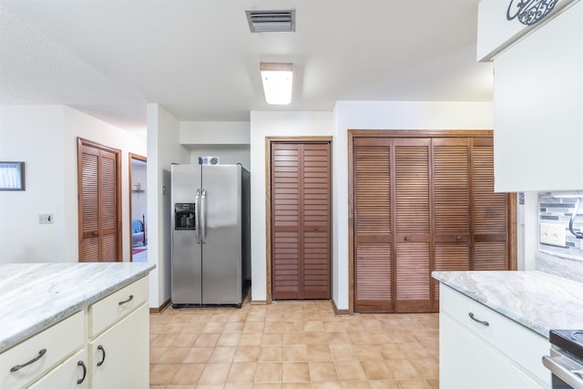 kitchen with stainless steel refrigerator with ice dispenser, stove, and white cabinets