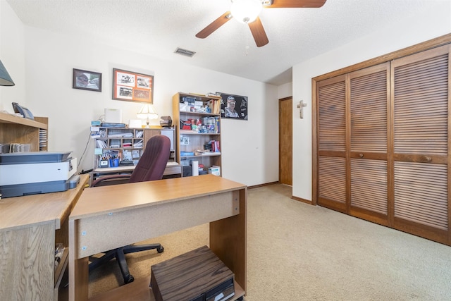 carpeted office space featuring a textured ceiling and ceiling fan