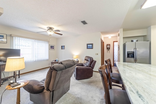 carpeted living room featuring ceiling fan and a textured ceiling