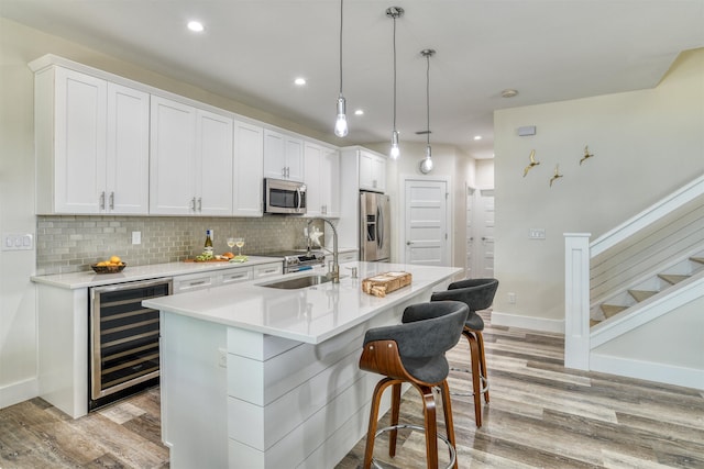 kitchen featuring stainless steel appliances, sink, pendant lighting, white cabinets, and wine cooler