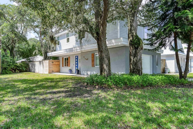 view of front of house with a front lawn, fence, and stucco siding