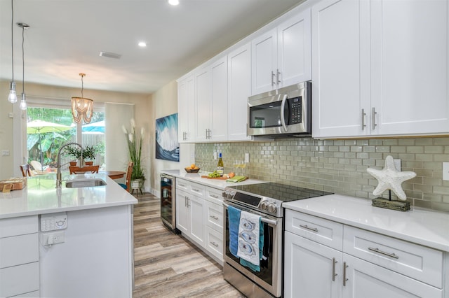 401 B St, Saint Augustine, FL 32080 - kitchen with wine cooler, appliances with stainless steel finishes, light wood-style floors, white cabinets, and a sink