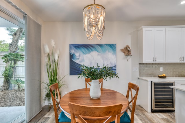 dining room featuring beverage cooler, a notable chandelier, and light wood-type flooring