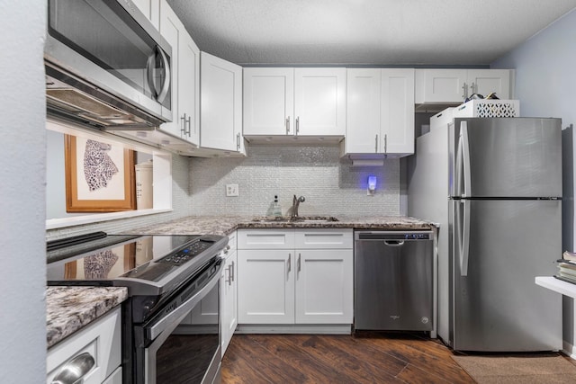 640 N Nova Rd Unit 117, Ormond Beach, FL 32174 - kitchen with appliances with stainless steel finishes, white cabinets, light stone countertops, tasteful backsplash, and dark wood-style flooring