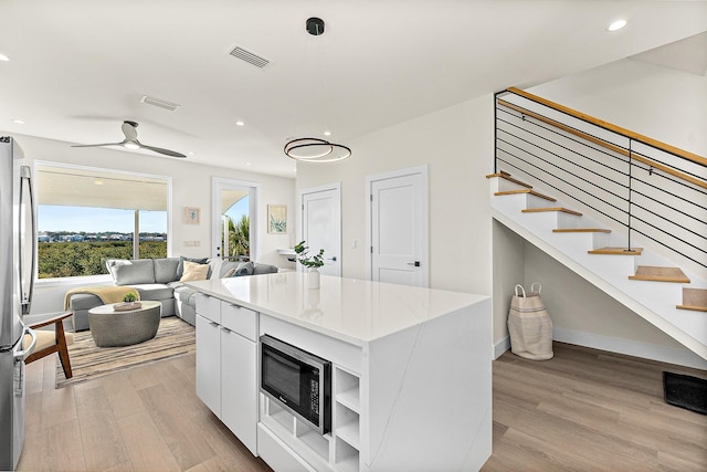 kitchen with hanging light fixtures, light hardwood / wood-style flooring, ceiling fan, appliances with stainless steel finishes, and white cabinetry