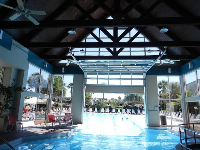 pool with glass enclosure, ceiling fan, and a patio