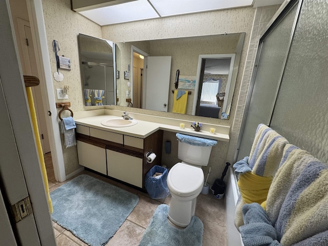 bathroom featuring tile patterned flooring, a shower with shower door, vanity, and toilet