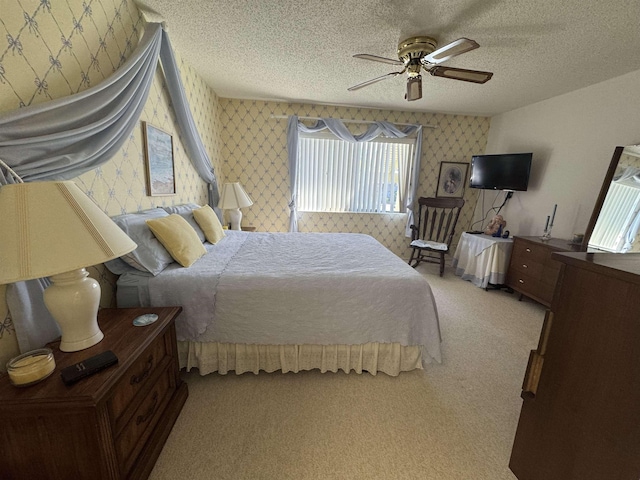 bedroom featuring a textured ceiling, ceiling fan, carpet flooring, and wallpapered walls