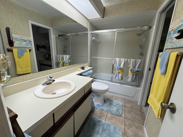 bathroom with toilet, vanity, bath / shower combo with glass door, and tile patterned floors