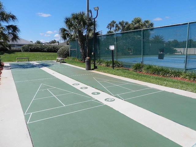 view of property's community with shuffleboard and fence