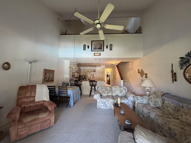 living area featuring ceiling fan, stairs, a high ceiling, and light colored carpet