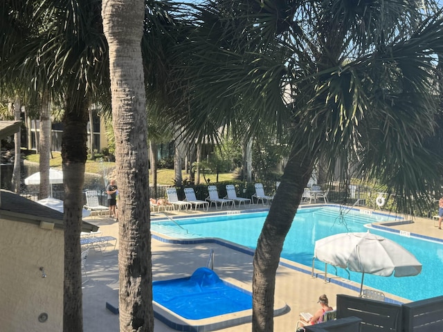 community pool with a patio area and fence