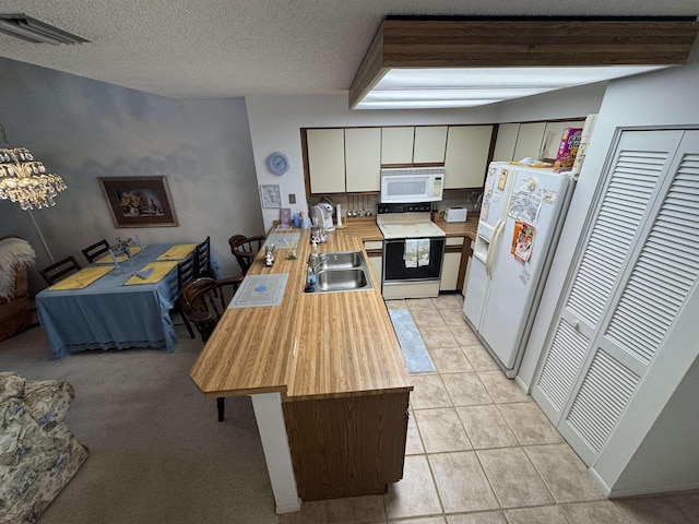 kitchen with white appliances, light tile patterned floors, visible vents, a peninsula, and a sink