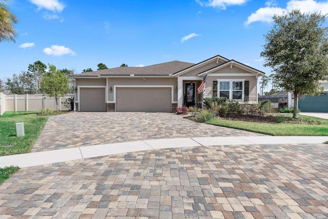 view of front facade with a garage, stone siding, fence, and decorative driveway