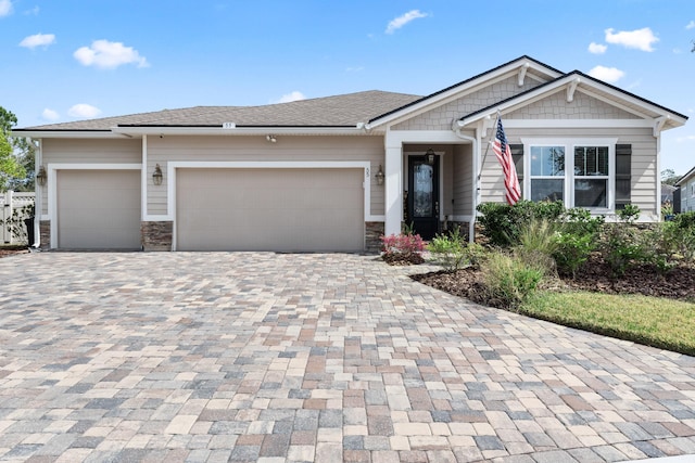 view of front of property with a garage, stone siding, and decorative driveway