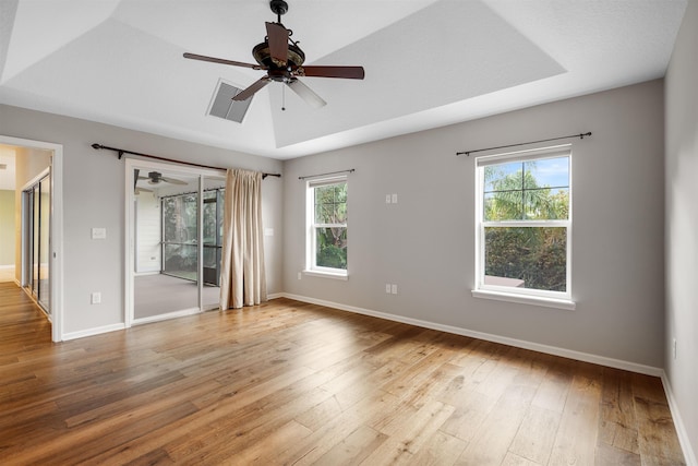 unfurnished room with a raised ceiling, light hardwood / wood-style flooring, a wealth of natural light, and ceiling fan