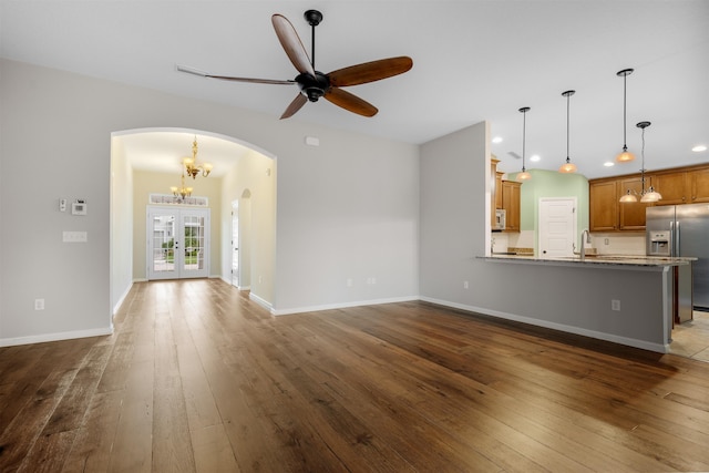 unfurnished living room with french doors, ceiling fan with notable chandelier, dark hardwood / wood-style floors, and sink