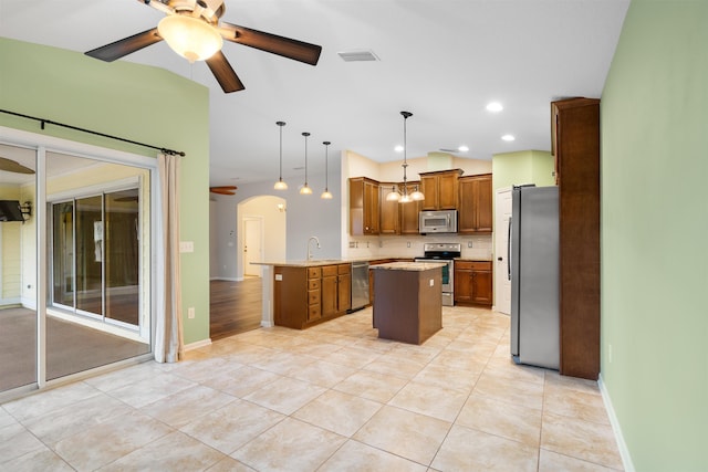 kitchen featuring ceiling fan, a center island, stainless steel appliances, kitchen peninsula, and pendant lighting