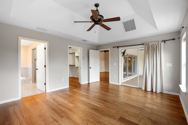 unfurnished bedroom featuring a walk in closet, ensuite bath, ceiling fan, light hardwood / wood-style flooring, and a closet