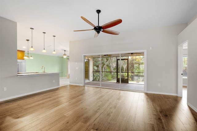 unfurnished living room featuring sink, light wood-type flooring, plenty of natural light, and ceiling fan