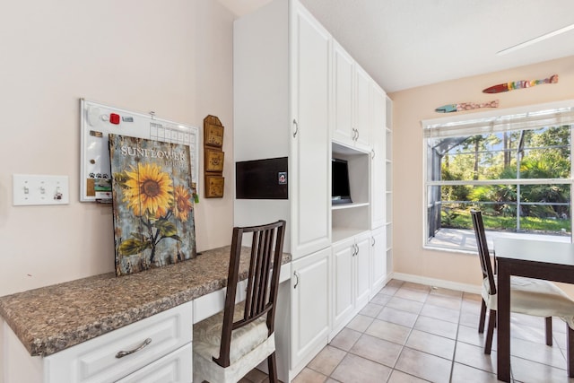 kitchen featuring dark stone countertops, white cabinets, and light tile patterned flooring