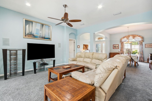 carpeted living room featuring ceiling fan with notable chandelier