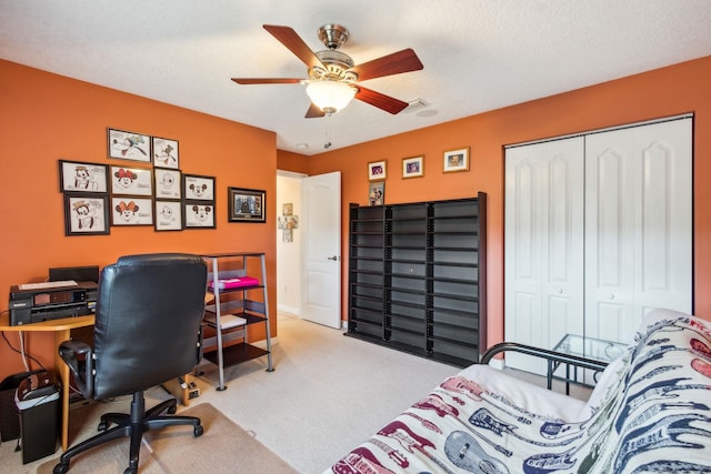 bedroom with ceiling fan, light colored carpet, a textured ceiling, and a closet