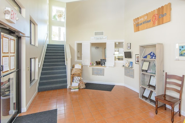 4250 A1A Unit E31, Saint Augustine Beach, FL 32080 - entrance foyer with a towering ceiling, tile patterned flooring, stairway, and baseboards