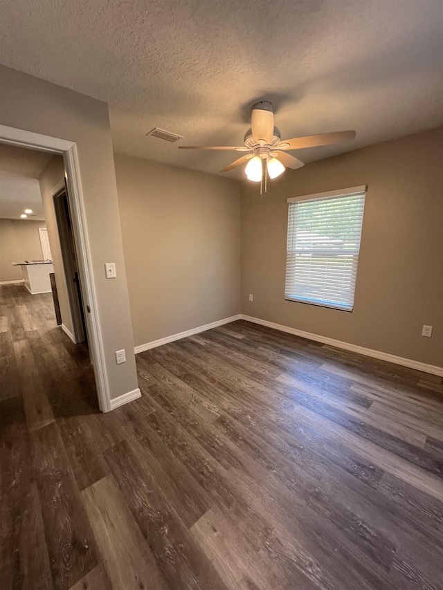 unfurnished room with ceiling fan, a textured ceiling, and dark hardwood / wood-style floors