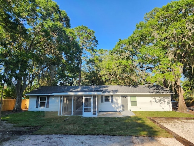 rear view of property with a sunroom, a lawn, and a patio