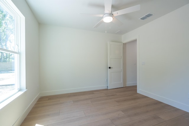 empty room featuring visible vents, light wood finished floors, baseboards, and ceiling fan