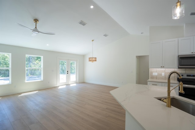 kitchen with backsplash, vaulted ceiling, a ceiling fan, a sink, and stainless steel microwave