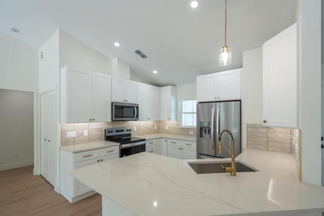 kitchen with lofted ceiling, stainless steel appliances, visible vents, a sink, and a peninsula