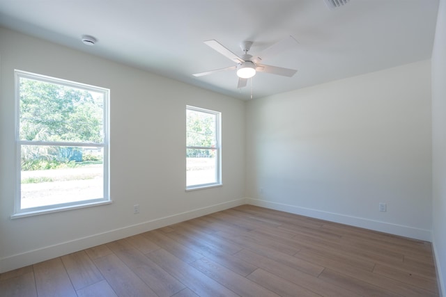 unfurnished room with wood finished floors, a ceiling fan, and baseboards