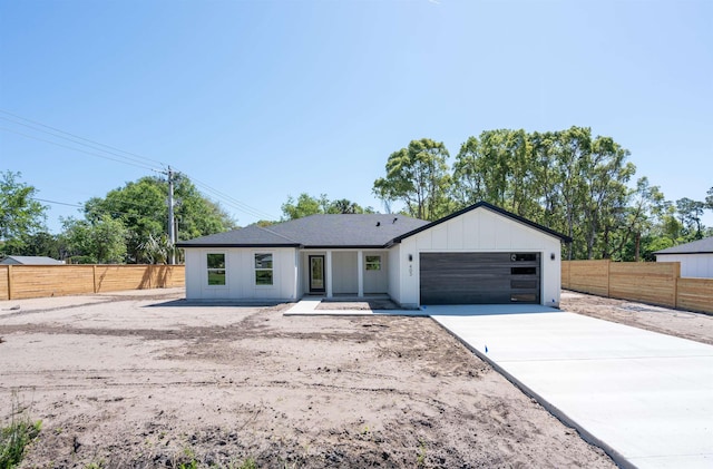 ranch-style house featuring concrete driveway, an attached garage, fence, and board and batten siding