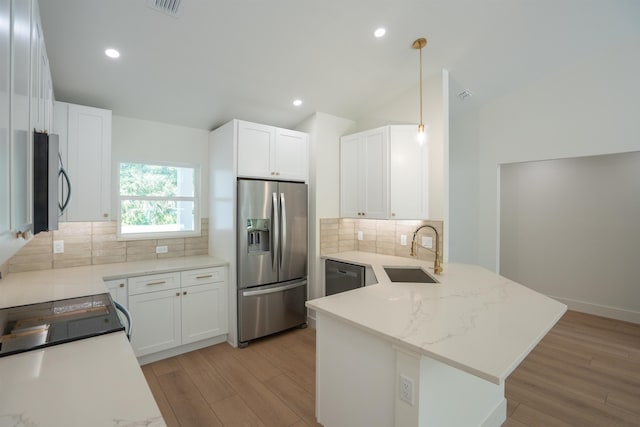 kitchen with tasteful backsplash, a sink, light wood finished floors, a peninsula, and appliances with stainless steel finishes