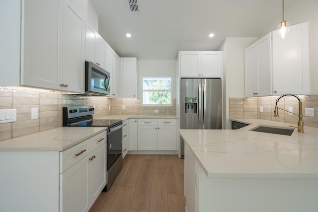 kitchen featuring stainless steel appliances, a sink, visible vents, decorative backsplash, and light stone counters