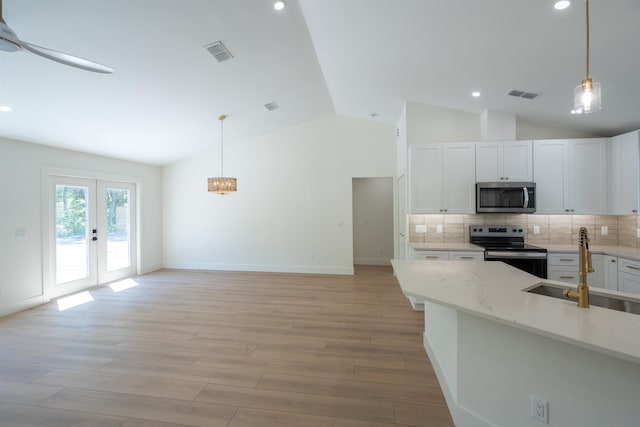 kitchen featuring vaulted ceiling, a sink, light wood finished floors, appliances with stainless steel finishes, and visible vents