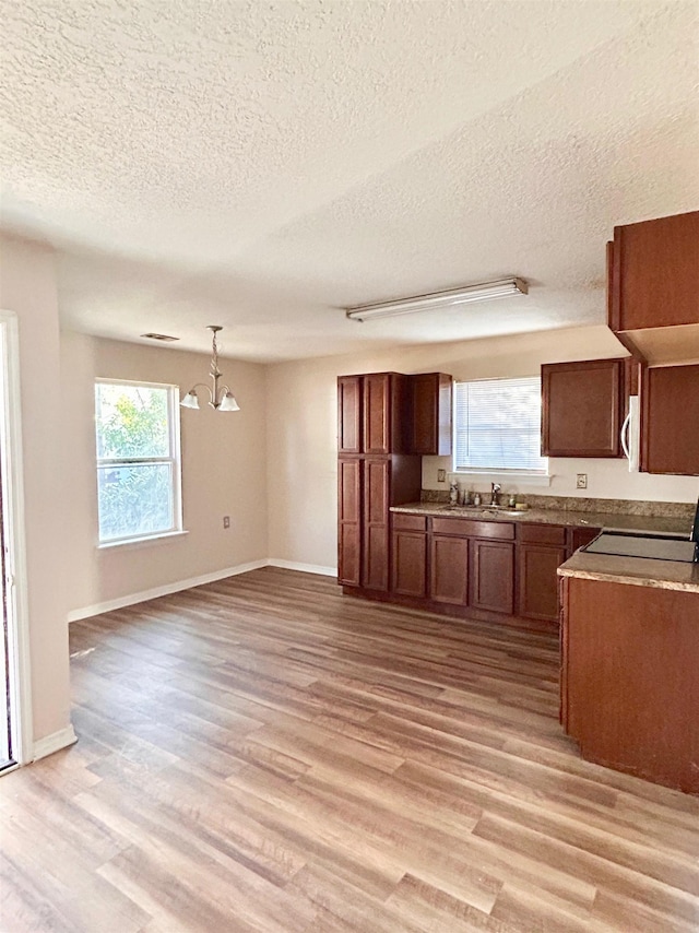 kitchen featuring pendant lighting, sink, a notable chandelier, light hardwood / wood-style floors, and range