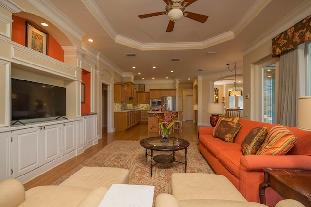 living area featuring light wood finished floors, a tray ceiling, a ceiling fan, and recessed lighting