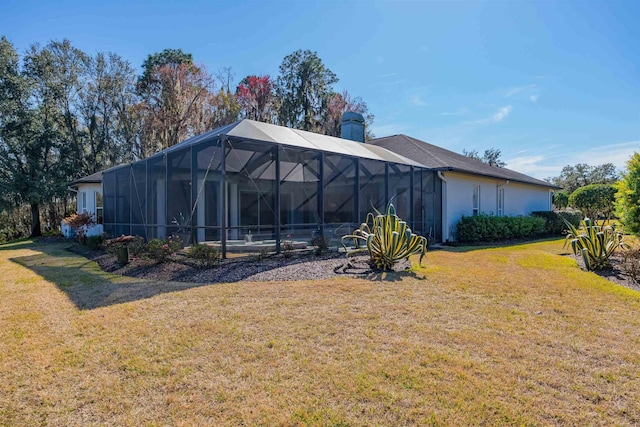 rear view of property featuring a yard, a chimney, a lanai, and stucco siding