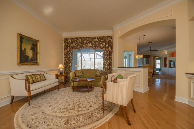 sitting room featuring baseboards, crown molding, and wood finished floors