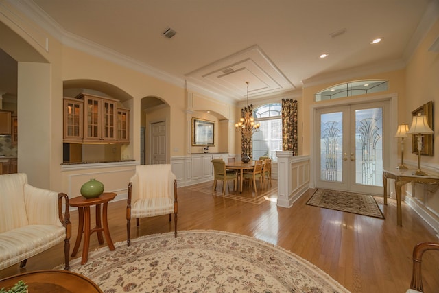 entrance foyer featuring french doors, a wainscoted wall, crown molding, visible vents, and light wood-style floors