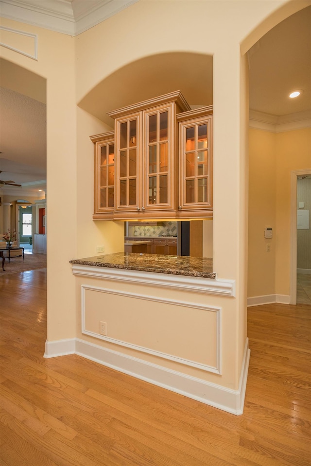 interior space featuring ornamental molding, wood finished floors, a ceiling fan, and baseboards