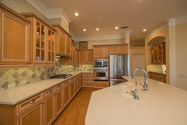 kitchen with visible vents, decorative backsplash, appliances with stainless steel finishes, a sink, and light wood-type flooring