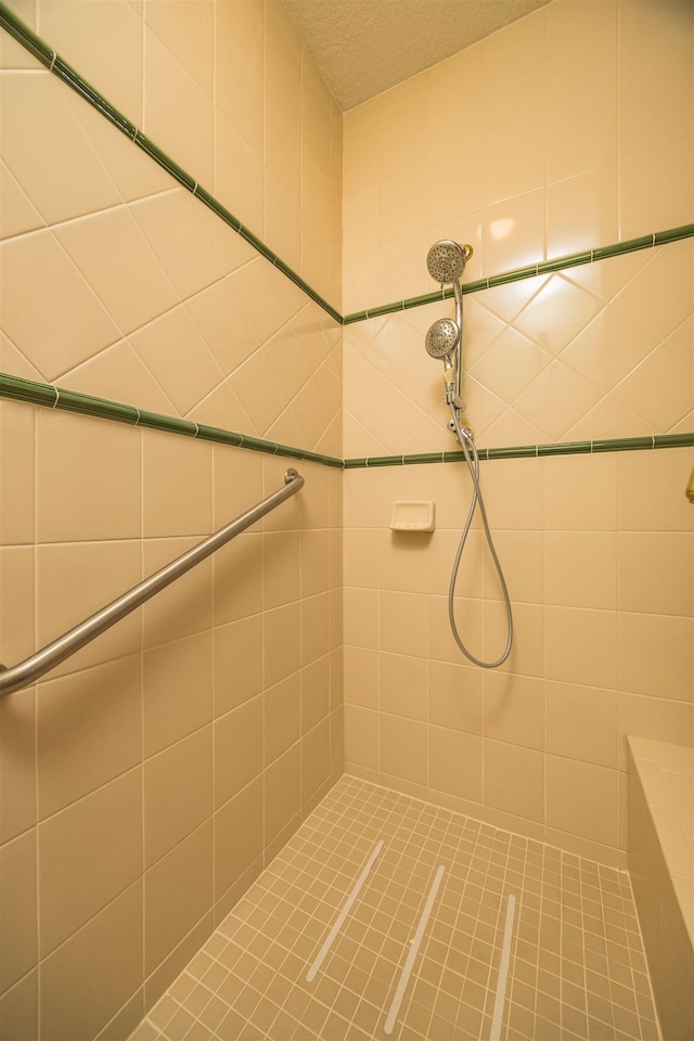 bathroom with a textured ceiling and tiled shower