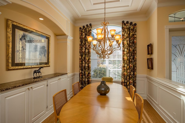 dining space with a chandelier, a wainscoted wall, crown molding, and a decorative wall